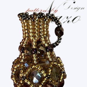 Puede incluir: Un cántaro de cuentas doradas y marrones con un diseño de cristal transparente. El cántaro tiene una pequeña asa y está decorado con cuentas marrones.