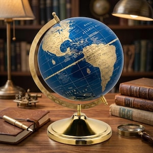 Puede incluir: Un globo terráqueo de escritorio con océanos de color azul profundo y continentes dorados. El globo está montado sobre un anillo meridiano de metal dorado pulido y una base circular. El mapa muestra etiquetas geográficas en texto dorado.