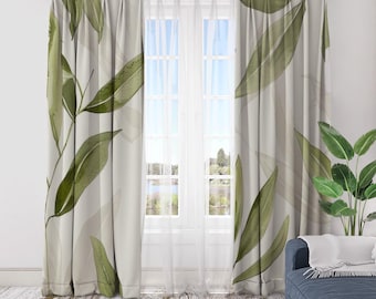 May include: A pair of light beige curtains with a watercolor-style leaf design in shades of green. The curtains hang in front of a window with sheer white panels, and a blue sofa is visible in the corner. The curtains add a touch of nature to the room.