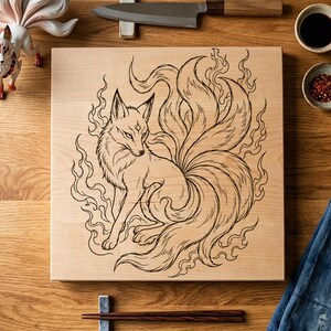 May include: A square wooden cutting board featuring a laser-engraved illustration of a nine-tailed fox surrounded by stylized flames. The board is displayed alongside a white ceramic fox figurine, a kitchen knife, two small bowls, and chopsticks.