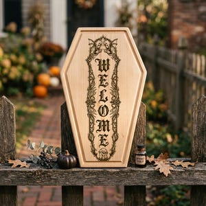 May include: A light-colored wooden sign shaped like a coffin featuring a vertical engraving of the word WELCOME in a gothic font, surrounded by intricate filigree and bat illustrations. The sign is displayed on a weathered wooden fence.
