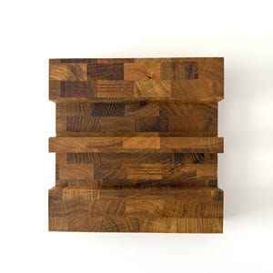K&ouml;nnte beinhalten: Ein handgefertigter Holzblock mit Stufen-Design. Der Block besteht aus verschiedenen Holzst&uuml;cken und erzeugt eine strukturierte Oberfl&auml;che mit warmer, nat&uuml;rlicher Farbe. Das Design weist eine Reihe horizontaler Stufen auf, die dem St&uuml;ck visuelles Interesse verleihen.