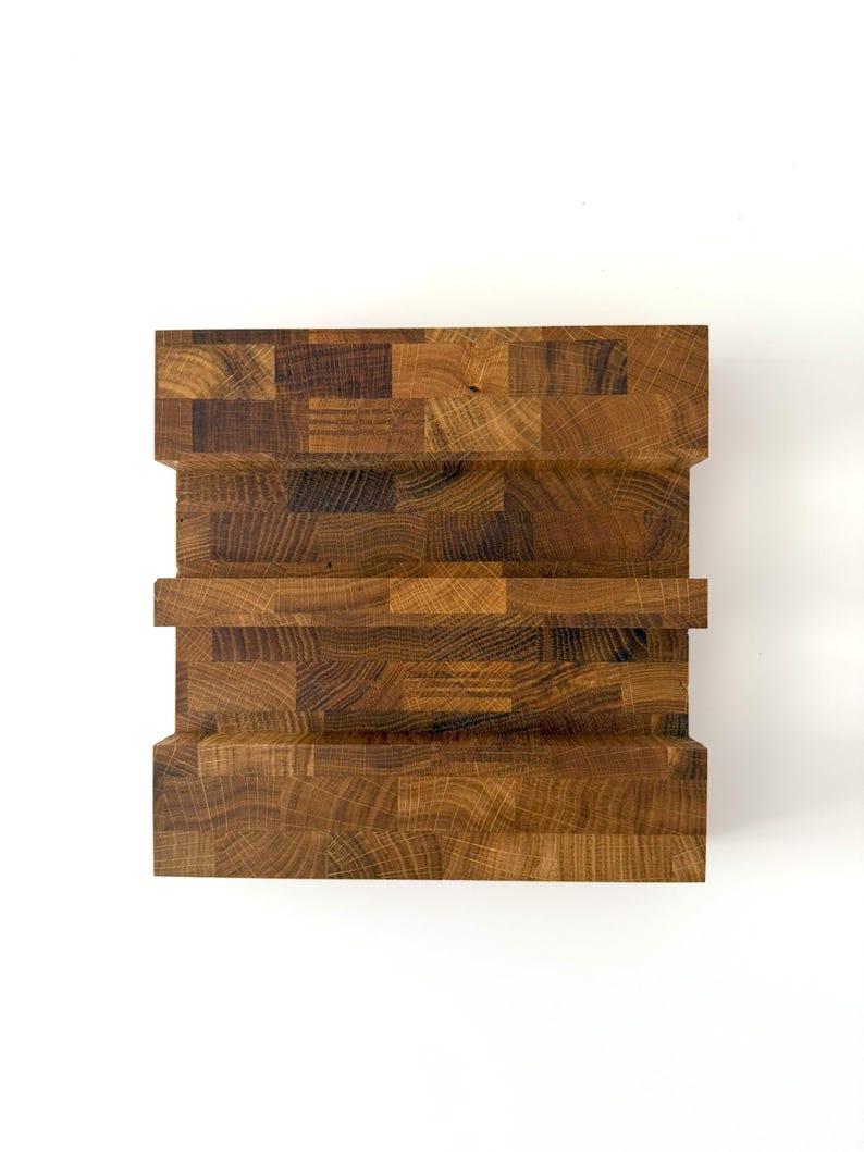 K&ouml;nnte beinhalten: Ein handgefertigter Holzblock mit Stufen-Design. Der Block besteht aus verschiedenen Holzst&uuml;cken und erzeugt eine strukturierte Oberfl&auml;che mit warmer, nat&uuml;rlicher Farbe. Das Design weist eine Reihe horizontaler Stufen auf, die dem St&uuml;ck visuelles Interesse verleihen.