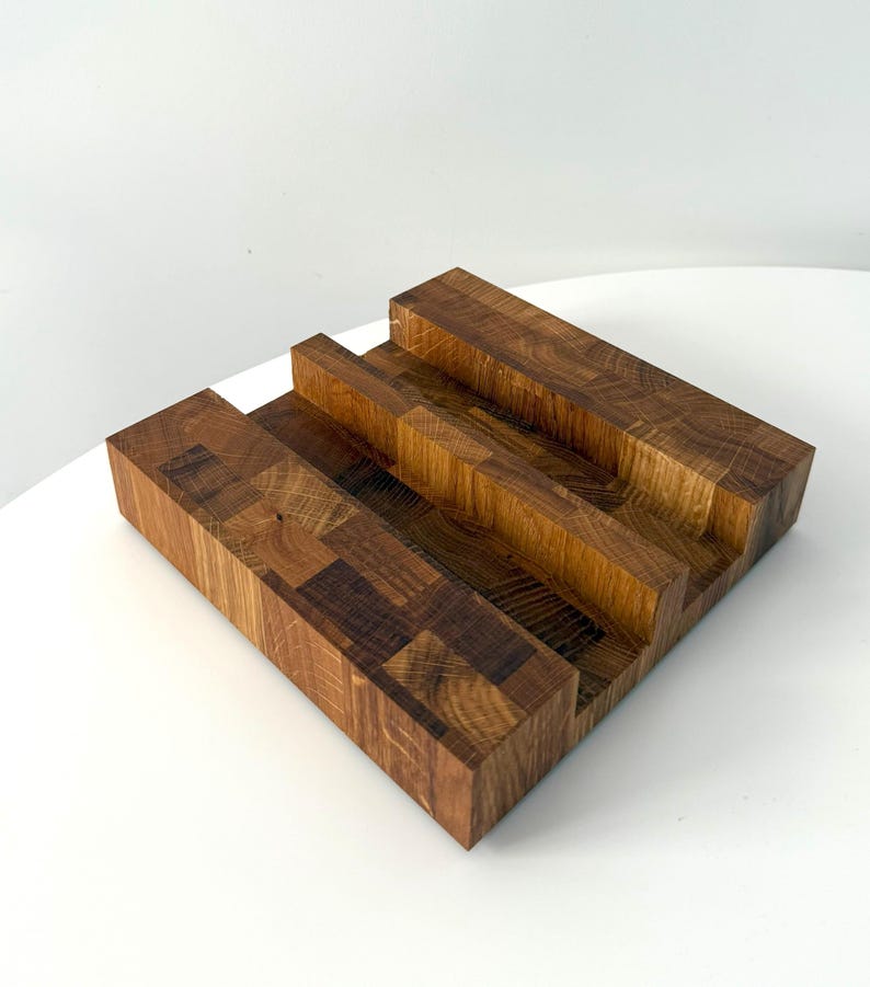K&ouml;nnte beinhalten: Ein handgefertigter Holzst&auml;nder mit einem mehrstufigen Design. Der St&auml;nder besteht aus verschiedenen Holzst&uuml;cken, wodurch ein mosaikartiges Muster entsteht. Die nat&uuml;rlichen Holzt&ouml;ne reichen von hell- bis dunkelbraun.
