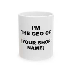 Op de afbeelding: Witte keramische mok met de tekst "I'M THE CEO OF [YOUR SHOP NAME]" in zwarte blokletters. De mok is cilindrisch en heeft een eenvoudig, strak ontwerp, geschikt voor koffie of thee.