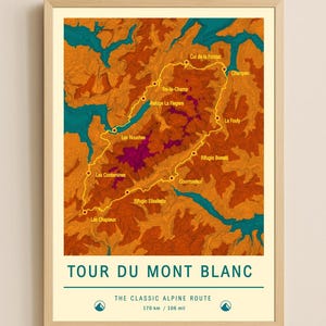 May include: A framed print of the Tour du Mont Blanc hiking route, featuring a topographic map in shades of orange, teal, and purple. The route is highlighted with a yellow line. Text at the bottom reads "TOUR DU MONT BLANC" and "THE CLASSIC ALPINE ROUTTE 170 km / 106 mi."