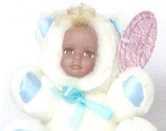 Foxy, a 5" plush blue and white teddy bear with a porcelain African American face with a dark blone curl, has real eyelashed