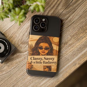 Könnte beinhalten: Schwarze iPhone-Hülle mit einem Retro-Grafik einer Frau mit Sonnenbrille und dem Text "Classy, Sassy & a little Badassy". Das Design hat eine Vintage-Ästhetik mit Sonne und Palmen.