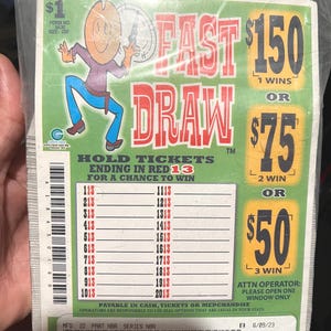 May include: A sealed pack of "Fast Draw" lottery tickets. The design features a cartoon cowboy with a lasso, the text "Fast Draw", and prize amounts of $150, $75, and $50. The tickets are marked with numbers ending in "13".