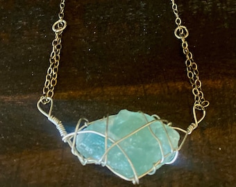 May include: A silver chain necklace with a turquoise stone wrapped in silver wire. The chain has small turquoise beads.