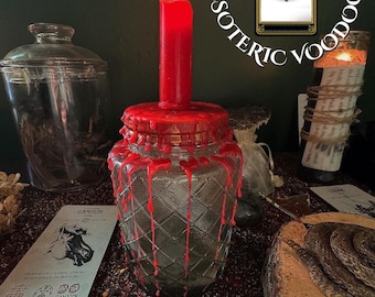 May include: A lit red candle sits atop a glass jar with a diamond pattern, surrounded by red wax drips. The words "ESOTERIC VOODOO" are arched above. Tarot cards and other ritualistic items are arranged around the jar, creating a mystical atmosphere.