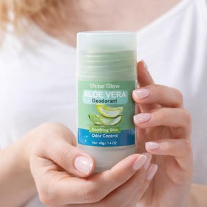 May include: A cylindrical deodorant stick with a light green top and a white base. The label reads "Shine Glow Aloe Vera Deodorant" with aloe vera slices. The net weight is 1.4 oz.