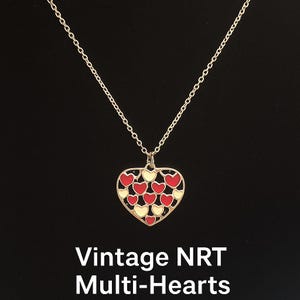 May include: A silver-toned necklace with a heart-shaped pendant. The pendant is filled with red and cream-colored hearts. The necklace has the text "Vintage NRT Multi-Hearts" at the bottom.