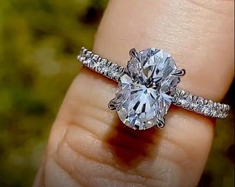 Anillo de compromiso con moissanita ovalada y diamantes en forma de cesta de oro.