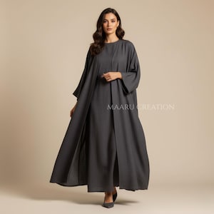 May include: A dark gray, floor-length dress with a matching open-front overcoat. The dress has a round neckline and long sleeves. The overcoat has wide sleeves and a split front. The text "MAARU CREATION" is visible on the right side.