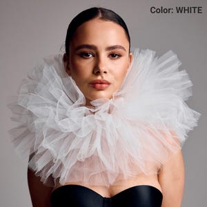 May include: A white tulle collar with multiple layers, creating a voluminous, ruffled effect. The model is wearing a black top. The text "Color: WHITE" is visible in the upper right corner.