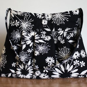 May include: A black and white floral tote bag with two straps. The bag has a large, rectangular shape and features a white floral pattern on a black background.