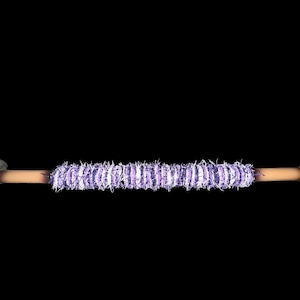 May include: A decorative, handcrafted object with a light brown central rod, capped with dark gray, rounded end pieces. The center is wrapped with a textured, light purple and white material. The background is solid black.