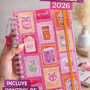May include: A pink spiral-bound reading journal for 2026, featuring a collage of stamp-like illustrations. The journal includes the text "Reading Journal 2026" and "INCLUYE CONTROL DE GASTOS Audiolibros + EBooks". The cover art includes images of jam jars, books, and other reading-related items.
