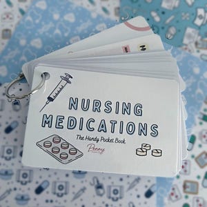 May include: A white flashcard set on a metal ring titled Nursing Medications The Handy Pocket Book by Penny Paper Co. The card features illustrations of a syringe, a blister pack of pills, and loose tablets in blue and black ink.