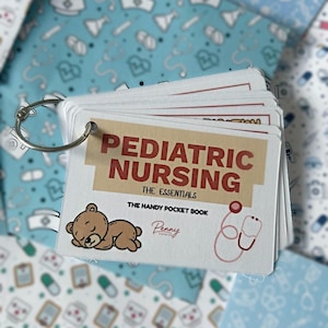 May include: A set of white flashcards bound by a silver metal ring. The top card features the text PEDIATRIC NURSING THE ESSENTIALS THE HANDY POCKET BOOK, a brown teddy bear illustration, and a pink stethoscope graphic on a tan background.