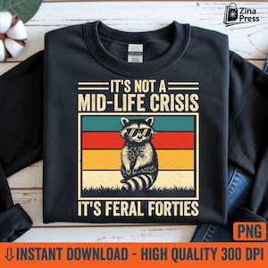 Pode incluir: Camisola preta com um gráfico de um guaxinim usando óculos de sol, em um design retrô de blocos de cores. O texto diz "IT'S NOT A MID-LIFE CRISIS IT'S FERAL FORTIES". É um download digital.