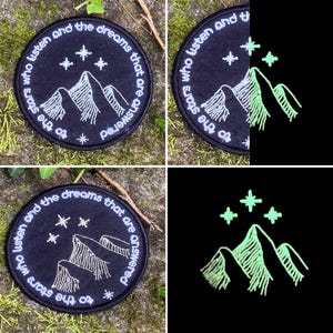 May include: A set of four round, black embroidered patches. Each patch features a mountain range and stars design with the text "to the stars who listen and the dreams that are answered" in white. One patch glows in the dark.