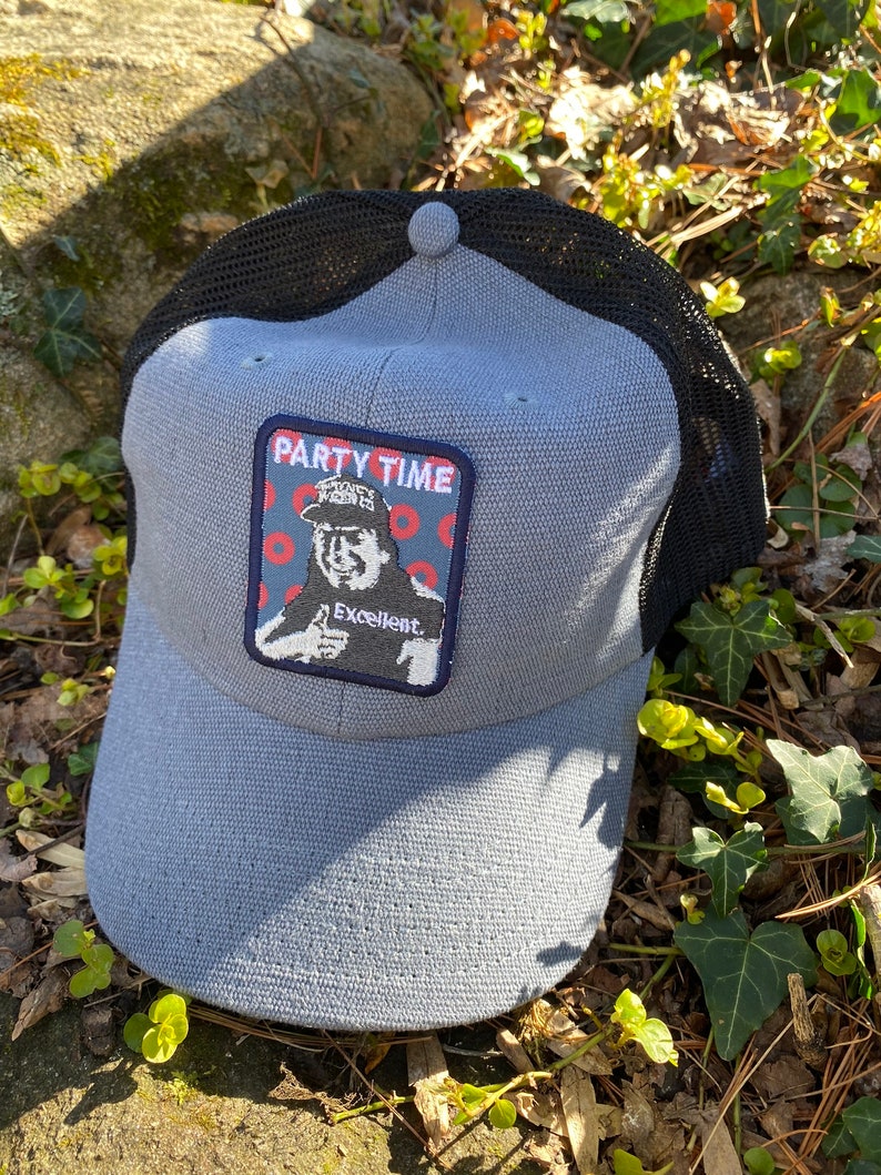 K&ouml;nnte beinhalten: Graue Baseballkappe mit schwarzem Mesh-R&uuml;cken. Die Kappe hat einen Aufn&auml;her mit den Worten "PARTY TIME" und einem Bild eines Mannes, der einen Daumen hochh&auml;lt. Das Wort "Excellent" steht ebenfalls auf dem Aufn&auml;her.