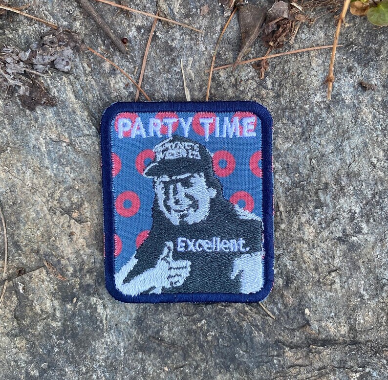 K&ouml;nnte beinhalten: Quadratischer Aufn&auml;her mit blauem Rand und blauem Hintergrund mit roten Donut-Formen. Der Aufn&auml;her zeigt ein Cartoon-Bild eines Mannes mit dem Text "PARTY TIME" oben und dem Wort "Excellent" darunter.