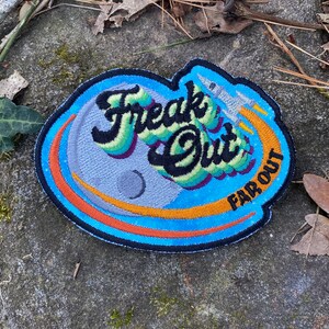 May include: Embroidered patch with the words "Freak Out" in a colorful, stylized font, with "Far Out" below. The design includes a rocket ship and a planet, set against a blue and orange background.