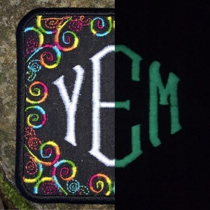 May include: Black rectangular patch with embroidered colorful swirls and the white letters YEM. The right side of the patch glows green with the letters YEM. The patch has a black border.