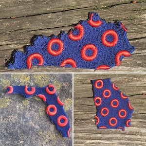 May include: Embroidered patches in the shapes of Kentucky, Florida, and Georgia. Each patch features a blue background with red circular designs. The patches are made of a textured fabric and are displayed on a wooden surface and a stone surface.