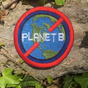 May include: Embroidered patch with a blue and green Earth design, encircled by a red and blue border. The words "PLANET B" are embroidered in white, with a red slash through the Earth, symbolizing a call to protect the planet.