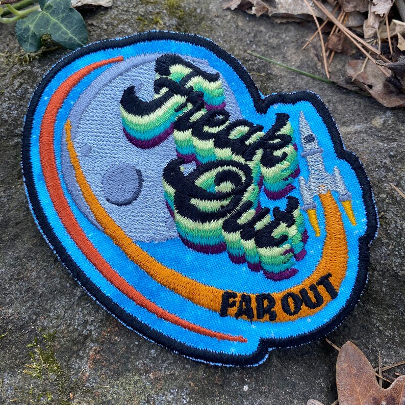 May include: Embroidered patch with a blue background and the words "Freak Out" in a colorful, wavy font. A rocket ship and the words "Far Out" are also featured. The patch has a retro, space-themed design.