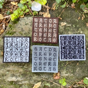 May include: Four square embroidered patches with the text "SATOR AREPO TENET OPERA ROTAS" in a grid pattern. The patches are in various colors: brown, white, gray, and black, with white or black lettering.