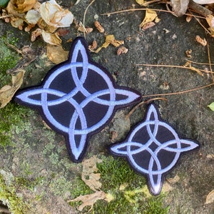 May include: Two black and light blue Celtic knot patches. The larger patch is approximately 4 inches in diameter, and the smaller patch is about 2.5 inches. The patches are embroidered with a light blue Celtic knot design.