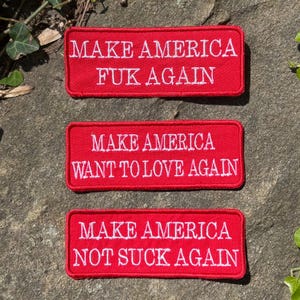 Może przedstawiać: Trzy czerwone prostokątne naszywki z białym haftowanym tekstem. Na naszywkach widnieją napisy "MAKE AMERICA FUK AGAIN", "MAKE AMERICA WANT TO LOVE AGAIN" i "MAKE AMERICA NOT SUCK AGAIN". Naszywki znajdują się na teksturowanej, szarej powierzchni.