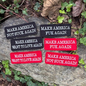 May include: Six rectangular embroidered patches featuring white text on black or red backgrounds. The text reads: MAKE AMERICA NOT SUCK AGAIN, MAKE AMERICA FUK AGAIN, or MAKE AMERICA WANT TO LOVE AGAIN. These patches have stitched borders.