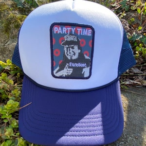 K&ouml;nnte beinhalten: Eine wei&szlig;e und marineblaue Trucker-M&uuml;tze mit Mesh-R&uuml;ckseite. Auf der Vorderseite befindet sich ein Aufn&auml;her mit den Worten "Party Time" und einem Bild eines Mannes, der den Daumen hochh&auml;lt, mit dem Wort "Excellent."