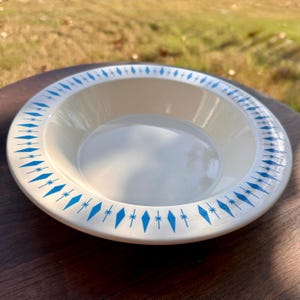 Puede incluir: Cuenco de cerámica color crema con un patrón de diamantes y estrellas azules en el borde. El cuenco es redondo y poco profundo, ideal para servir. Diámetro aproximado de 25 cm.