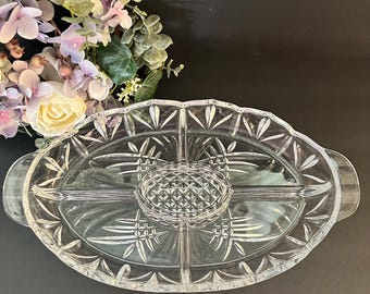 May include: Clear glass serving platter with a central dip bowl and four surrounding compartments. The oval-shaped platter has a scalloped edge and etched leaf and starburst designs. Includes two side handles.