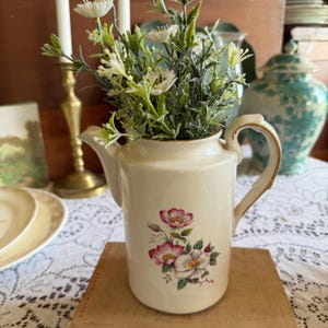 Puede incluir: Un juego de tres tazas de cerámica con un acabado moteado y mate. Las tazas son de color crema, gris claro y gris oscuro. Cada taza tiene un diseño simple y minimalista y un asa redondeada.