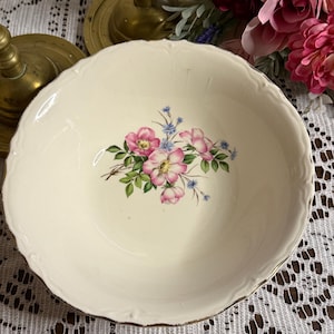 以下が含まれることがあります： クリーム色のセラミックボウル、スカラップエッジとゴールドトリム付き。ボウルの中央には、ピンクと青の花と緑の葉のフローラルデザインが施されています。ヴィンテージの装飾品です。