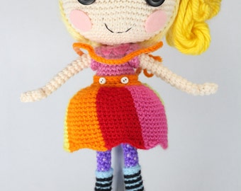 May include: A crocheted doll with yellow hair, a pink and red bow, and a colorful striped dress. The doll is wearing green boots with white toes and purple and white striped socks.