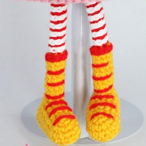 May include: Crocheted doll legs with red and white striped stockings and yellow shoes with red stripes.