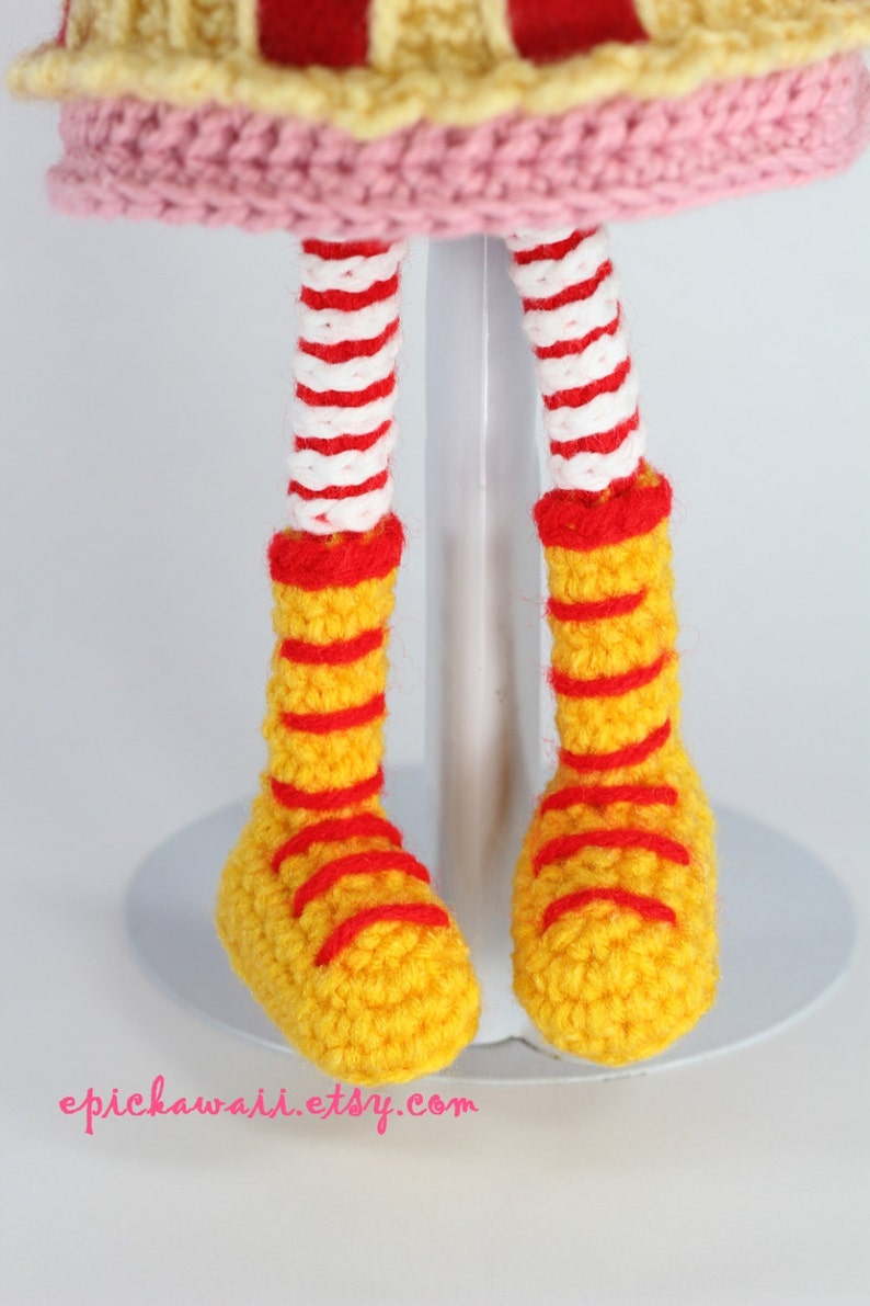 May include: Crocheted doll legs with red and white striped stockings and yellow shoes with red stripes.