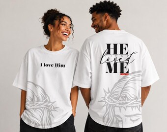 May include: White t-shirts with black text and a gray graphic. One shirt says "I love Him" and the other says "He first loved me" with a reference to 1 John 4:19. Both shirts have a gray graphic of a crown of thorns.