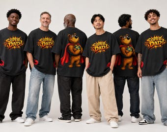 May include: Black t-shirts featuring a graphic of a brown bear wearing a red superhero cape and a blue emblem with the letter S on the chest, along with the text SUPER DAD in a yellow and orange comic book style burst on the front or back.