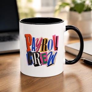 Peut inclure: Un mug en céramique blanche avec une anse et un bord intérieur noirs. L'avant présente le texte PAYROLL CREW dans un style collage multicolore, avec des lettres en rouge, rose, jaune, bleu et noir rappelant des coupures de magazines.