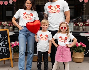 Pode incluir: Um conjunto de quatro camisetas brancas com gráficos de corações vermelhos e rosas com texto. Uma camiseta diz LOVE YOU MORE, uma diz LOVE YOU MOST, uma diz LOVE YOU MOSTEST e uma diz LOVE YOU. As camisetas são usadas com jeans azuis, calças pretas e uma saia rosa.